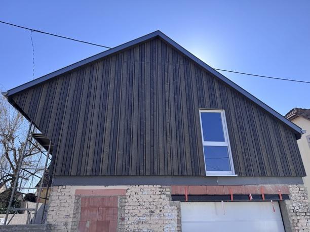 Bardage bois teinté foncé sur un pignon de maison
