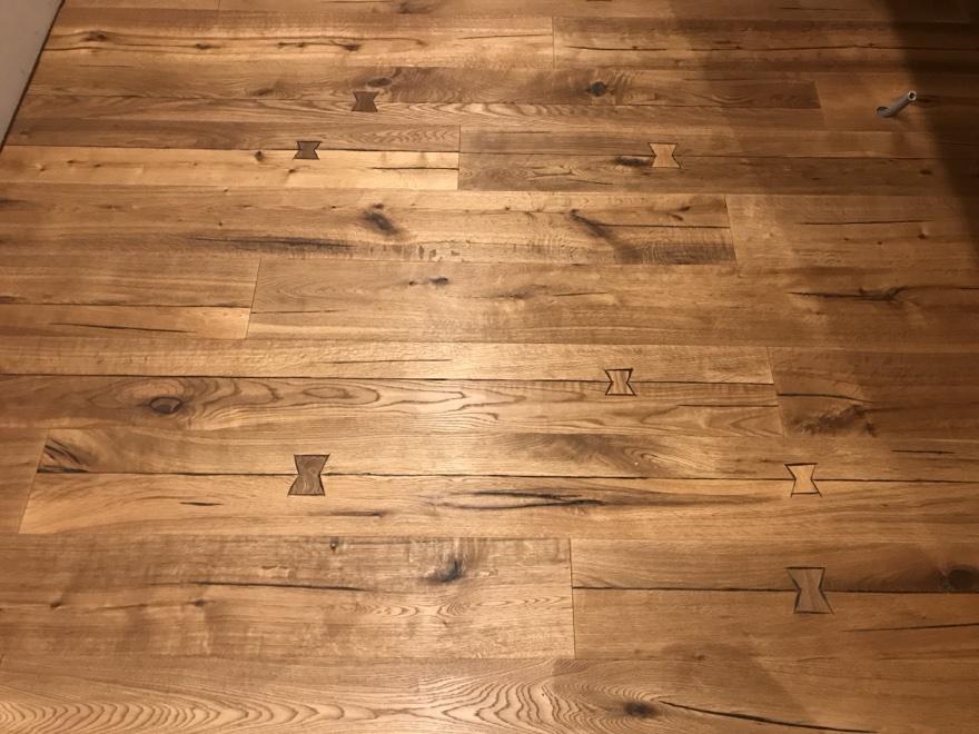 Détail d'un parquet bois avec inserts papillon décoratifs